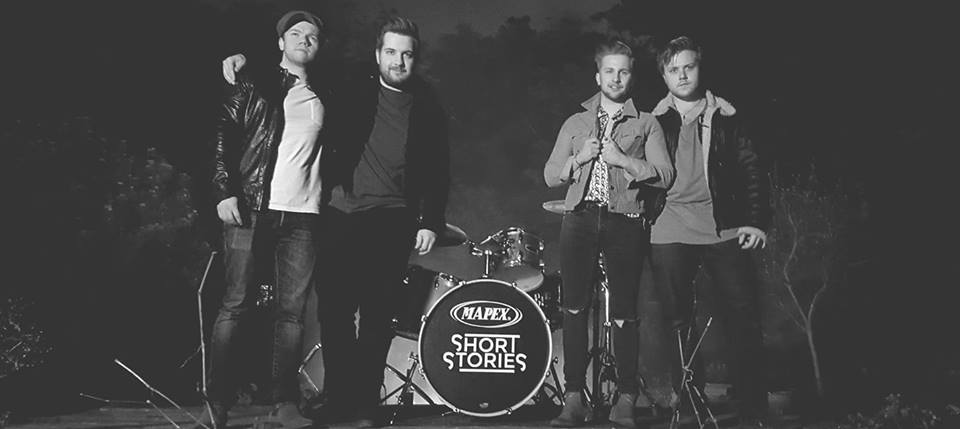 A black and white photo of four male band members posing in front of a drum set with the logo 'MAPEX' and text SHORT STORIES'.
